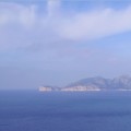 imagen de la costa de-Mallorca, con el mar azul, el cielo azul, y un brazo de tierra marrón y verde.