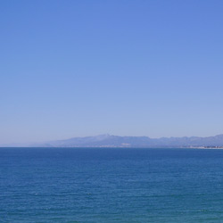 imagen del mar de Saluo, con la costa y la imagen de las montañas lejanas partiendo el mar del cielo.