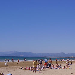 Playa-Levante, en-Salou. Abajo se ve la playa, con gente, y en la parte de arriba de la foto se ve mar, las montañas lejanasy y el cielo.